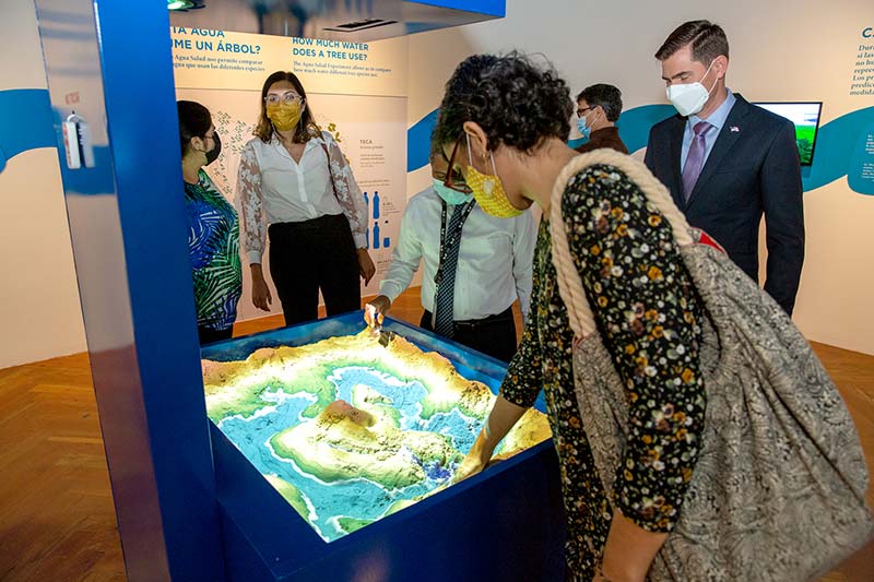 Durante la inauguración, Daney Ramírez y Lina González del Instituto Smithsonian de Investigaciones Tropicales y Christopher Bergaust, ministro consejero de la embajada de Estados Unidos, interactúan con el modelo de cuenca en la exhibición Agua Salud.